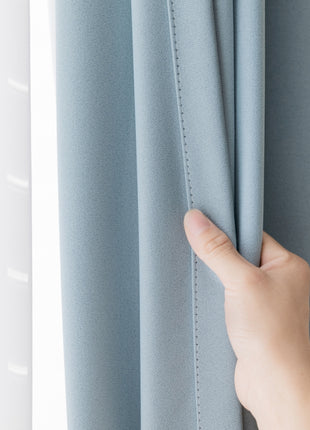 a person's hand is holding the curtain in front of a window