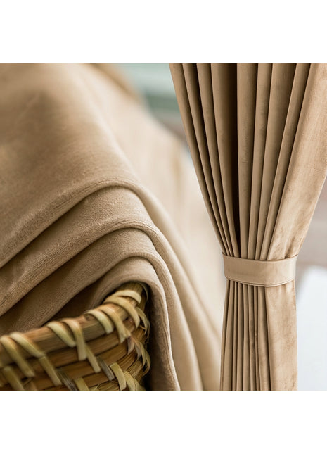 Rideau occultant en velours beige naturel drapé près d'un panier en rotin dans une chambre