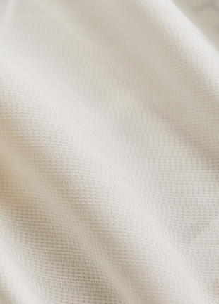 A close-up view of a soft, white fabric with a textured, woven appearance.