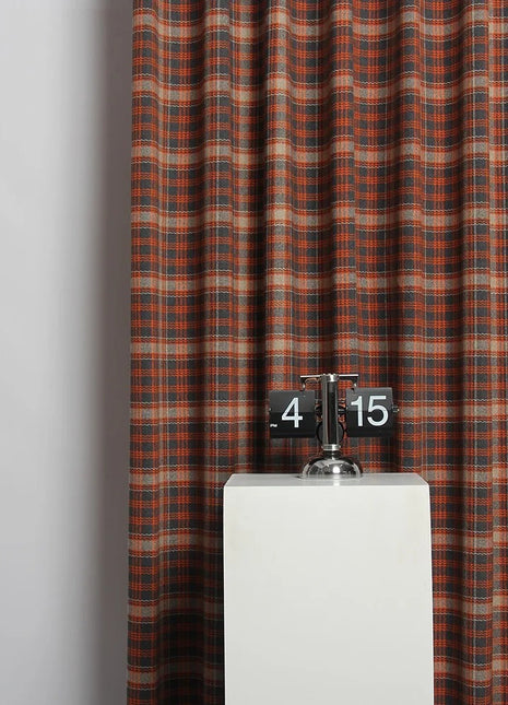 a clock on a pedestal in front of a curtain