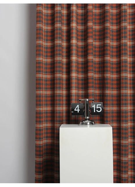 a clock on a pedestal in front of a curtain