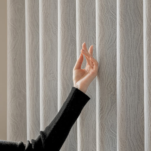 a woman's hand reaching up to a vertical blind