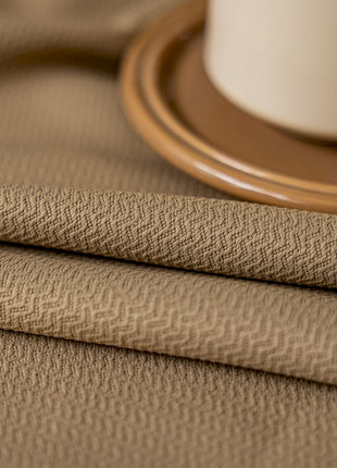 a close up of a table cloth with a cup of coffee in the background