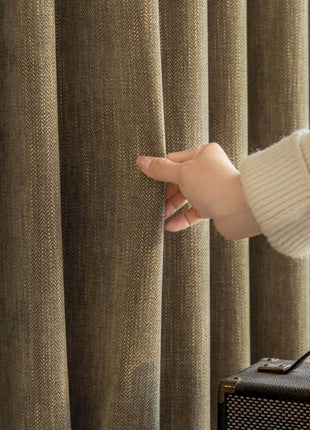 a person holding onto a curtain in front of a suitcase