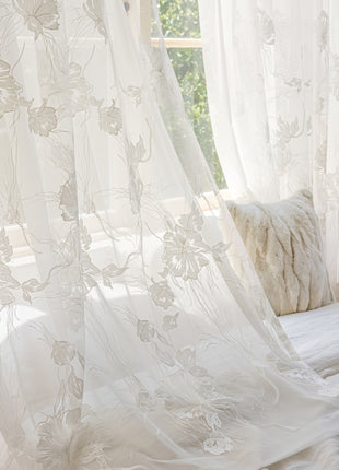 a bed with a white comforter and white curtains