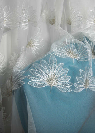 a blue and white curtain with white flowers on it