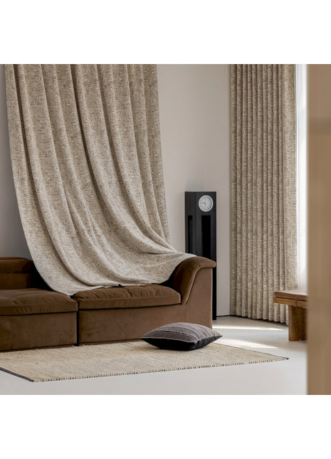 a living room with a brown couch and a tan curtain