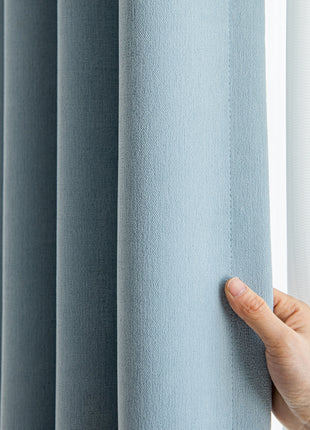 a hand is holding the curtain in front of a window