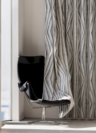 a chair sitting in front of a window next to a curtain