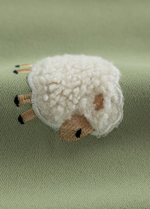 a small stuffed animal laying on top of a green blanket