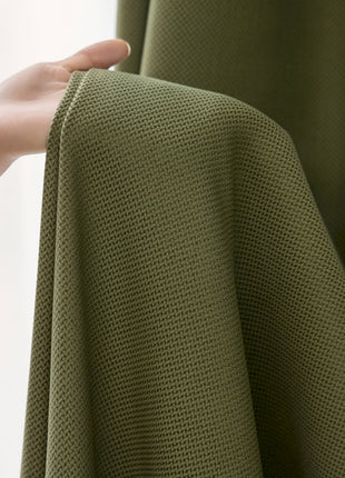 a person's hand is holding a green curtain