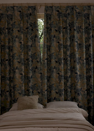 a bed sitting under a window next to a window covered in curtains