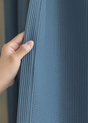 a person is holding the curtain with their hand