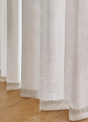 a close up of a curtain with a chair in the background