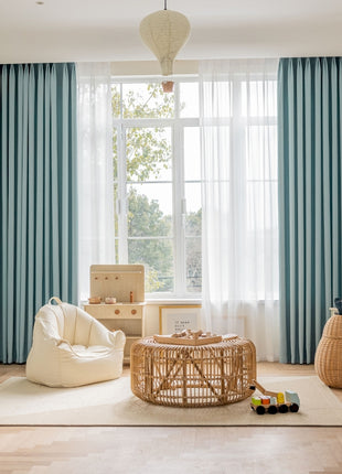 a child's room with a large window and a wicker chair