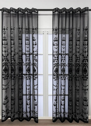 a living room with a window covered in black sheer curtains
