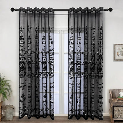 a living room with a window covered in black sheer curtains