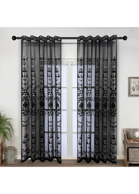a living room with a window covered in black sheer curtains