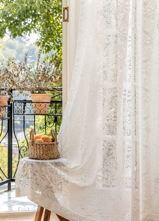 a window with a white curtain and a basket of fruit