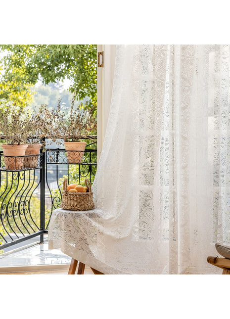 a window with a white curtain and a basket of fruit