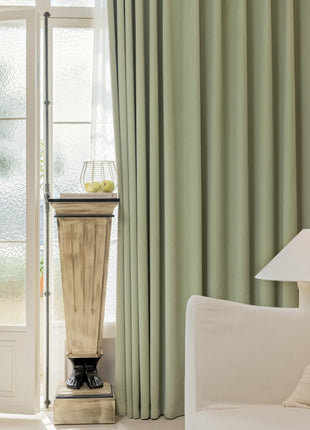 a living room with a white couch and green curtains