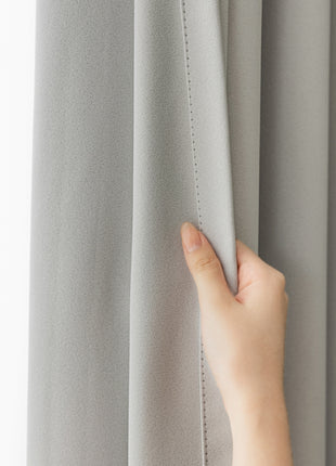 a person's hand on the curtain of a window