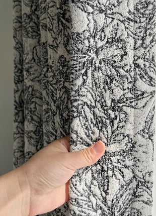 a person's hand is holding a curtain in front of a window