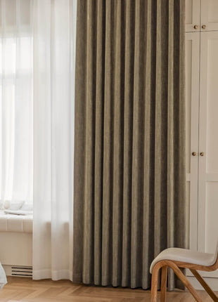 a bedroom with a bed, chair and curtains