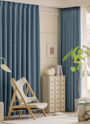 a living room with blue curtains and a white chair