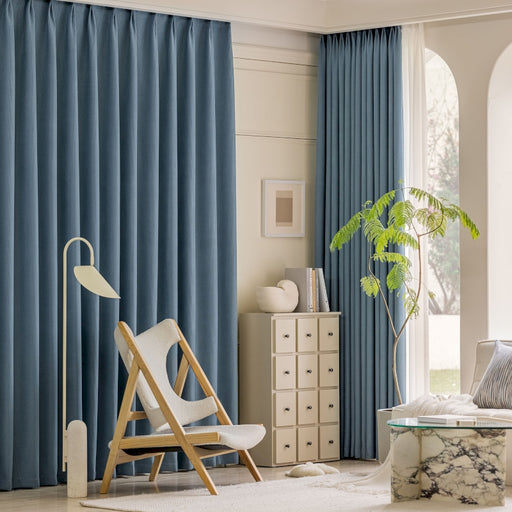 a living room with blue curtains and a white chair