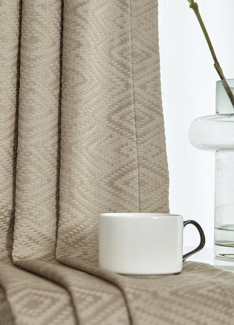 a coffee cup sitting on a table next to a vase of flowers