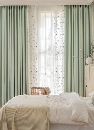 a bedroom with green curtains and a white bed