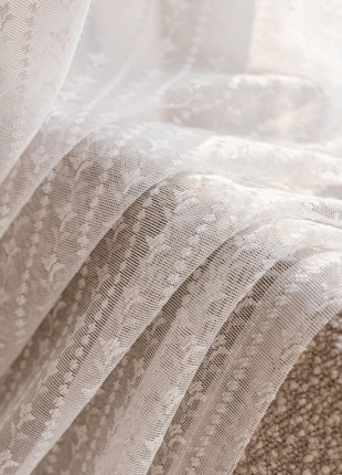 a close up of a bed with white lace on it