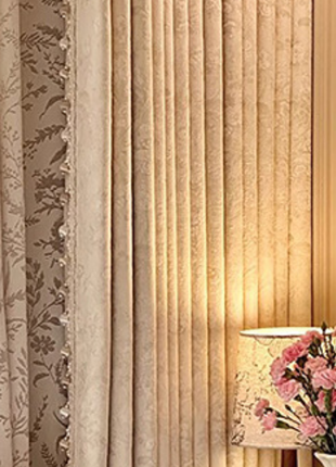 a window with a curtain and a lamp with pink flowers on a table.