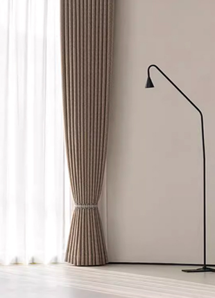 a minimalist interior design with a large window, a brown curtain, and a black floor lamp.