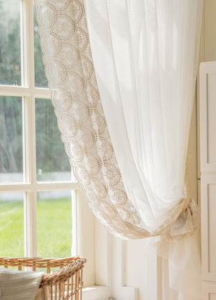 a window with a white curtain and a basket next to it
