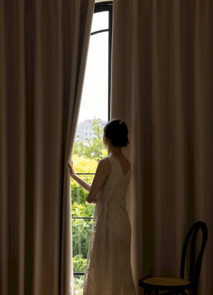 a woman in a wedding dress looking out a window