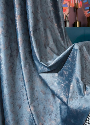 a bed with a checkered comforter and a blue curtain