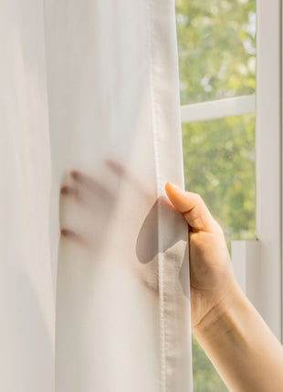 a person is holding a curtain in front of a window