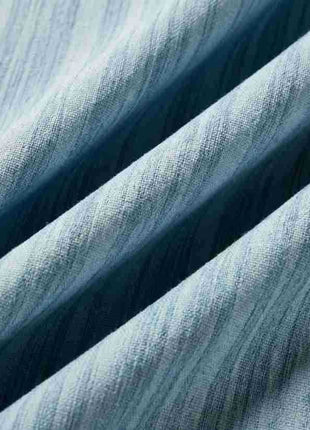 Plis serrés d'un rideau bleu ciel montrant le relief du tissage chiné