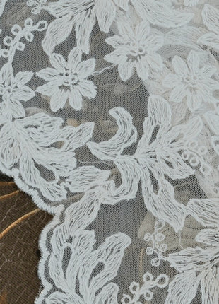 Gros plan de la broderie florale et du bord festonné du voilage