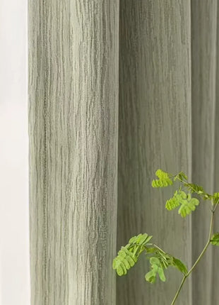 Rideau vert chenille au tissage strié, posé à côté d'un voilage blanc et d'une branche verte