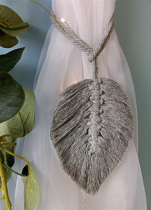 Un rideau blanc avec une feuille accrochée, mettant en valeur un style naturel et élégant. Corde d'attache disponible sur rideaux deco.