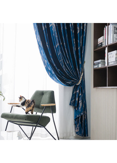 Rideau bleu paon à effet marbré retenu par une embrasse dorée dans un salon